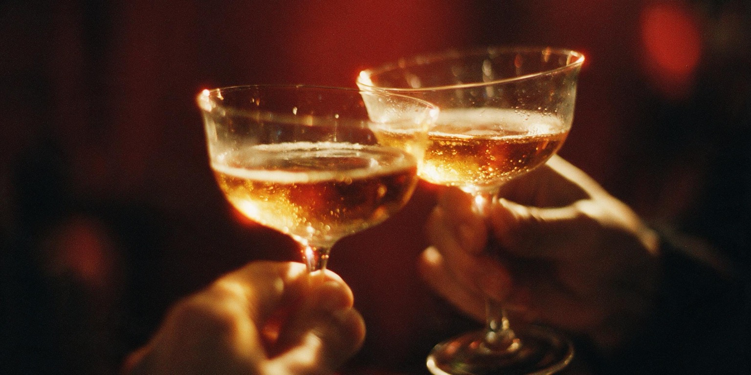 Two glasses meeting in the dark, lit red
