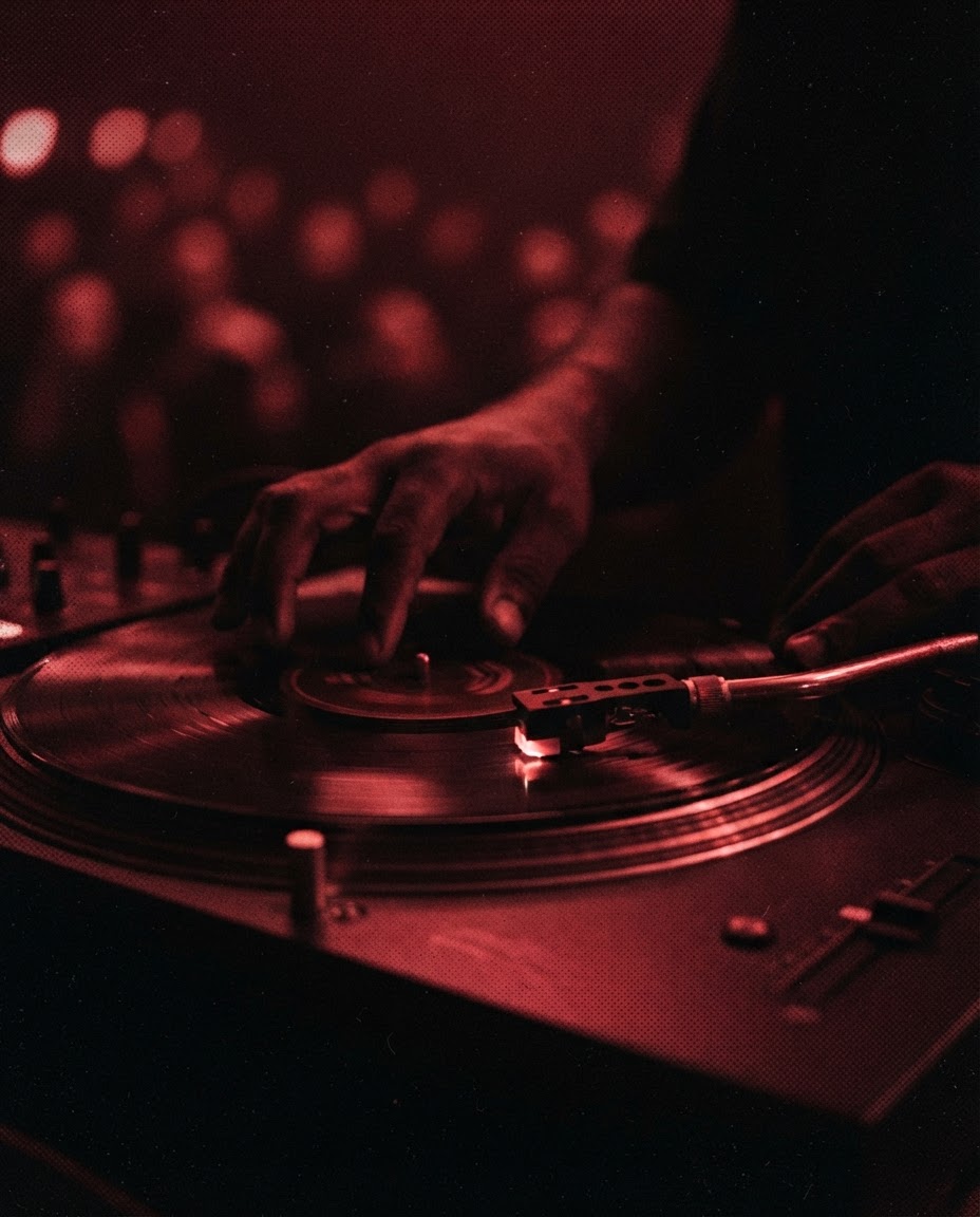 Hands on the turntable, the needle catching the red light